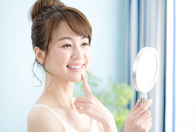 鏡で白い歯を確認して微笑む女性